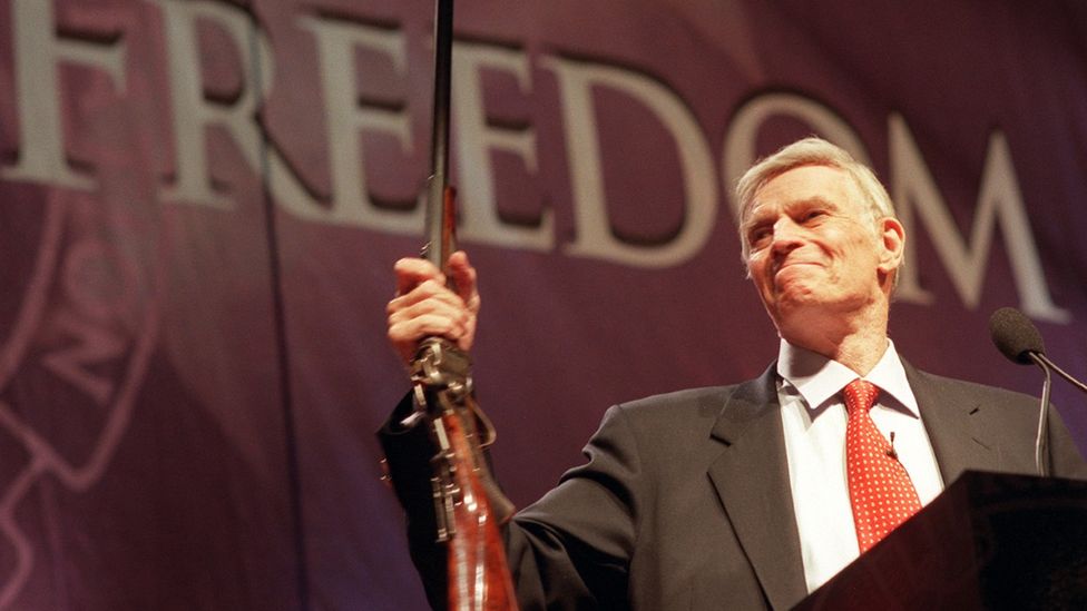 Actor Charlton Heston brandishes a rifle at an NRA meeting in 2002