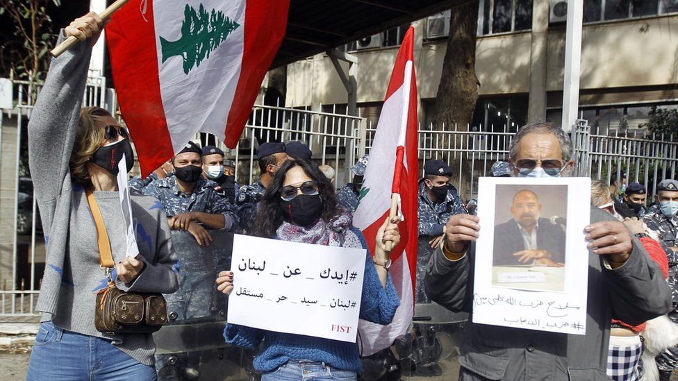 People holding photographs of Lokman Slim protest outside the Palais de Justice in Beirut, Lebanon