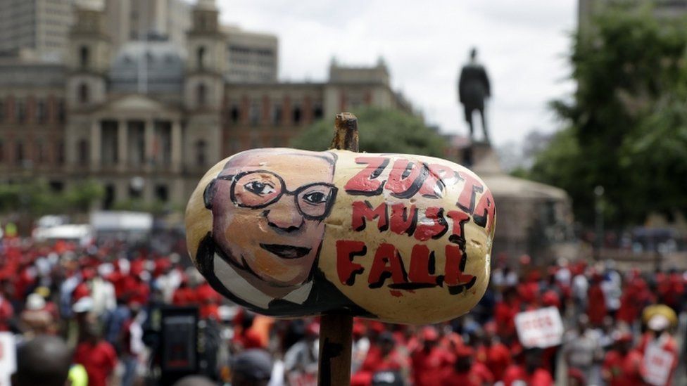 A protester holds a butternut squash painted with an image of South African President Jacob Zuma, during an anti-government march outside a court in Pretoria, South Africa, Wednesday, Nov. 2, 2016. Thousands of South Africans are demonstrating for the resignation of President Jacob Zuma, who has been enmeshed in scandals that critics say are undermining the country's democracy.