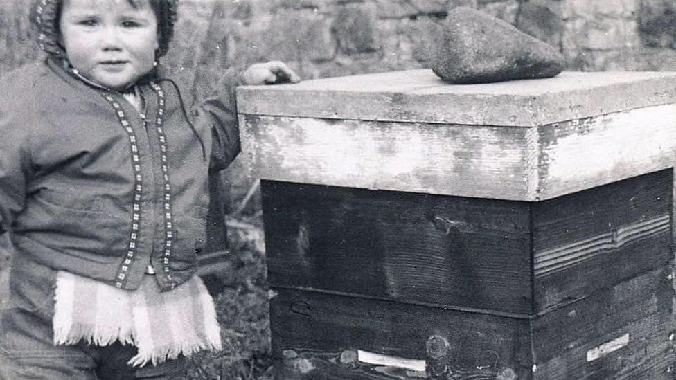 Stuart Hood as a toddler next to a bee hive
