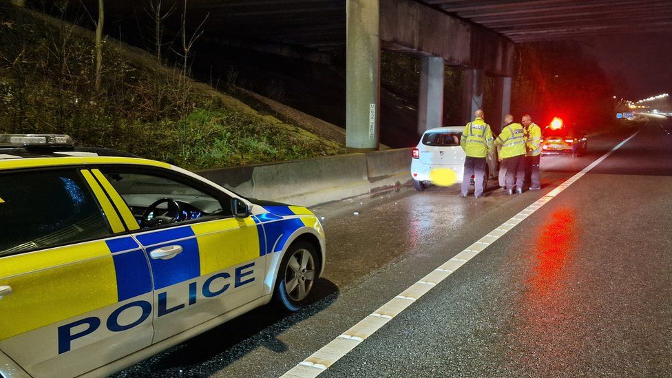 Police car stops white vehicle on M60