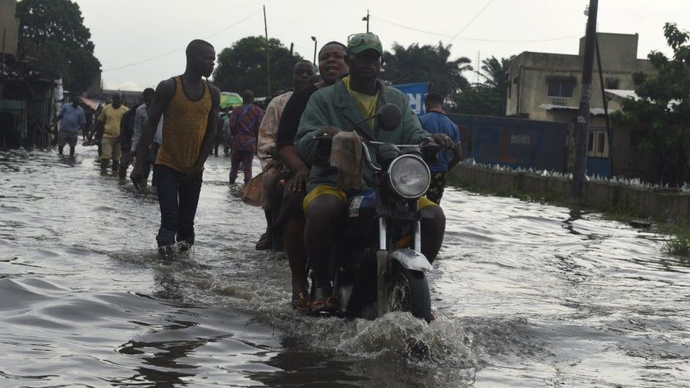 A taxi motocyclist rides on a flooded road at Okokomaiko in Ojo district of Lagos, on May 31, 2017.