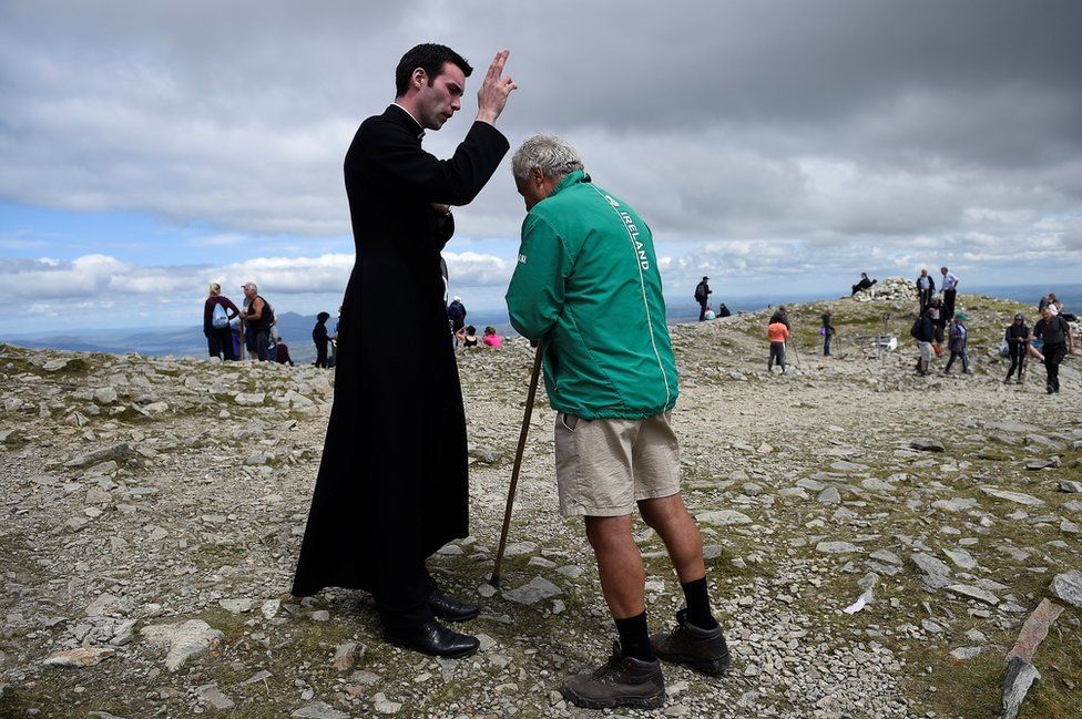 A pilgrim is blessed by the newly ordained Father Gerard Quirke after Mass at the summit of Croagh Patrick