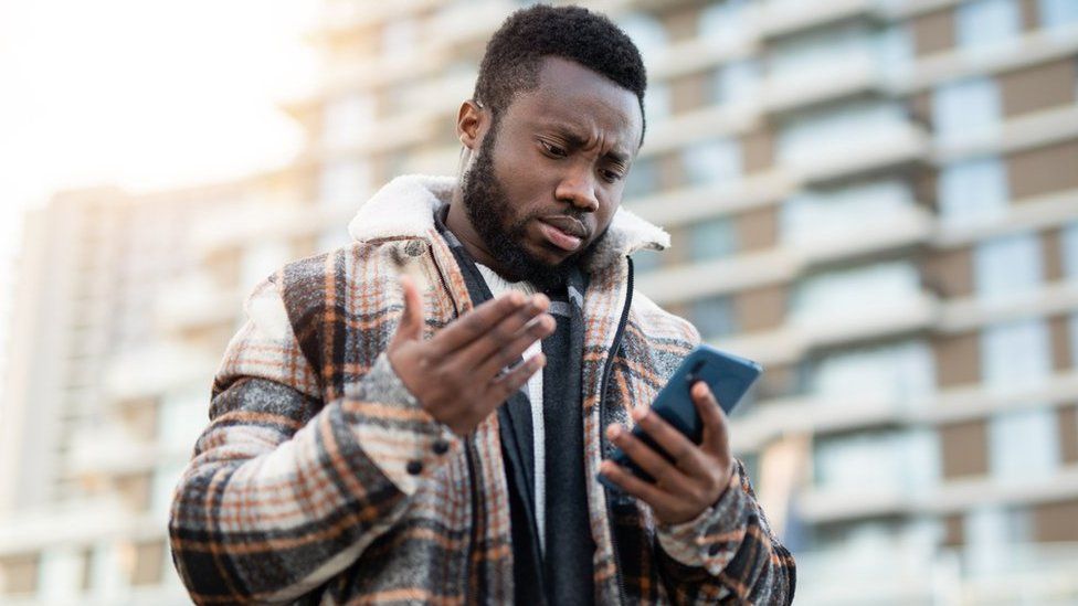 Person holding a smartphone looking frustrated