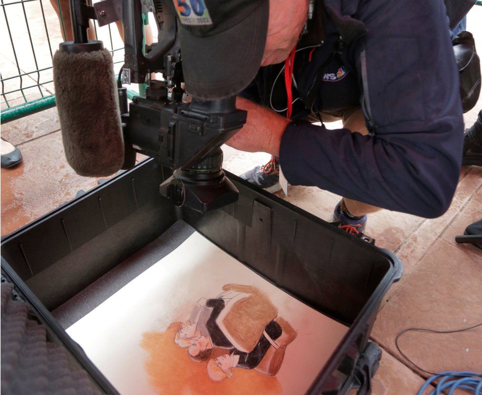 A photojournalist takes a photo of a courtroom artist's drawing