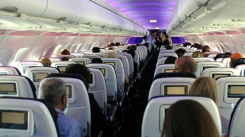 Passengers in custom-designed leather chairs enjoy Virgin America airlines mood-lit cabins and in-flight entertainment system