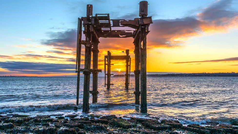 Sunrise through World War II pier head remains