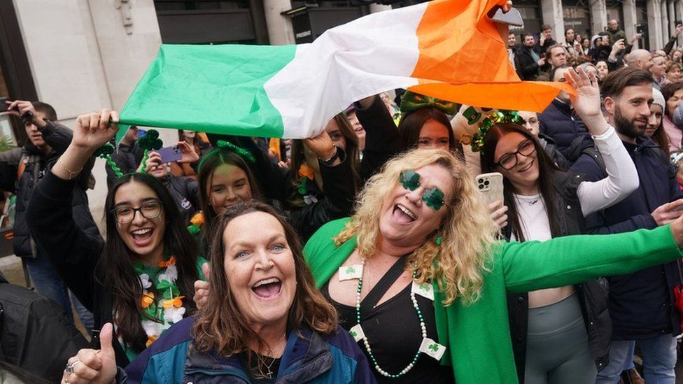 People holding up an Irish flag and smiling.