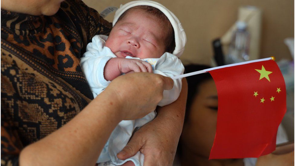 A woman carries a baby born on National Day at a hospital on 1 October, 2019 in Chengdu, Sichuan province