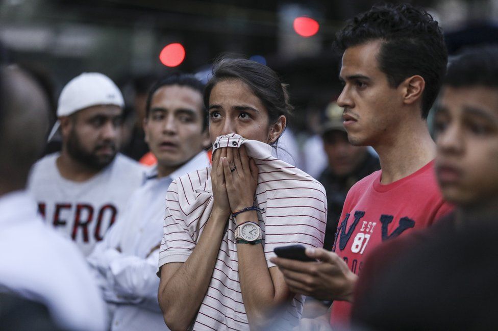 An upset young woman holds her shirt to her mouth in an anxious pose