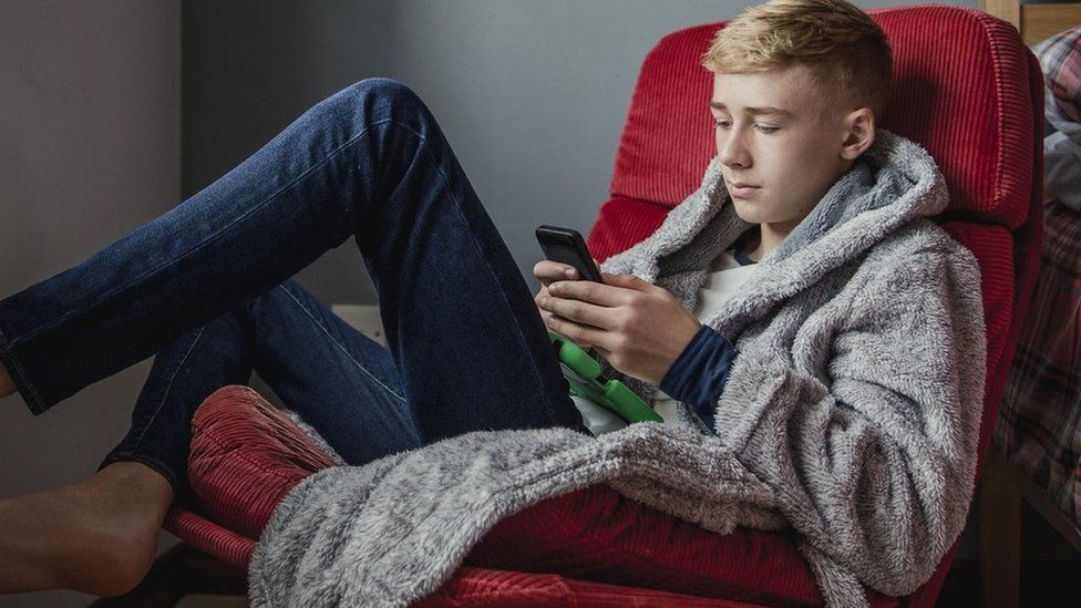 Teen using mobile phone in bedroom
