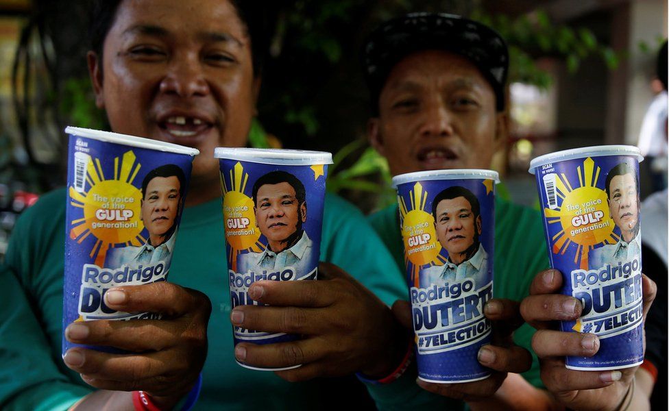 Two supporters of presidential candidate Rodrigo Duterte hold up two "Big Gulp" fizzy drink cups each, bought from 7-Eleven in Paranaque, Metro Manila, on 25 April