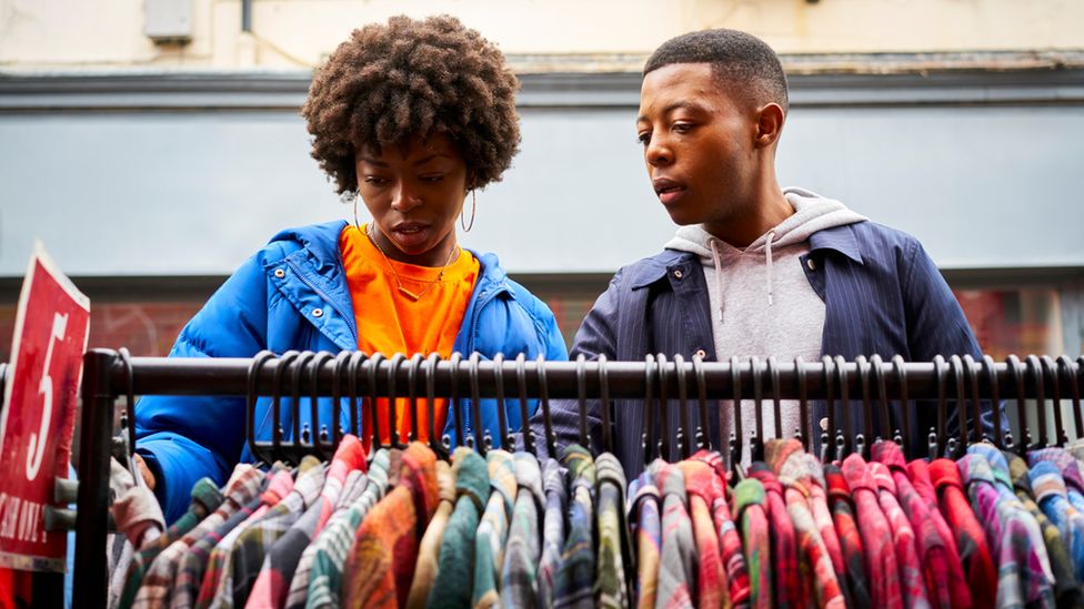 Two people shopping for clothes at a market