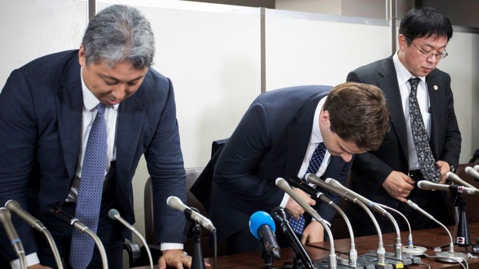Mark Karpeles (centre) bows at a press conference after appearing in court.