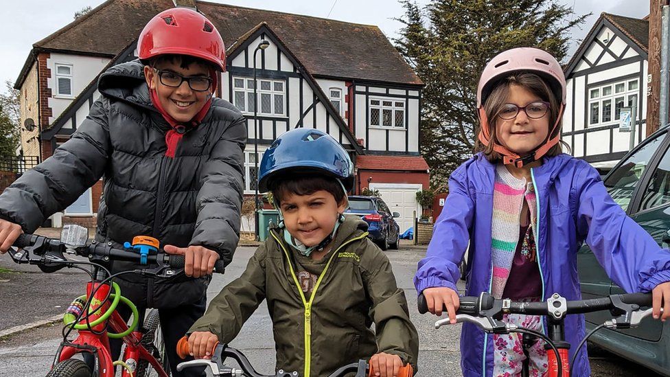 Kamran, Harris and Eve wearing helmets while riding their bikes.