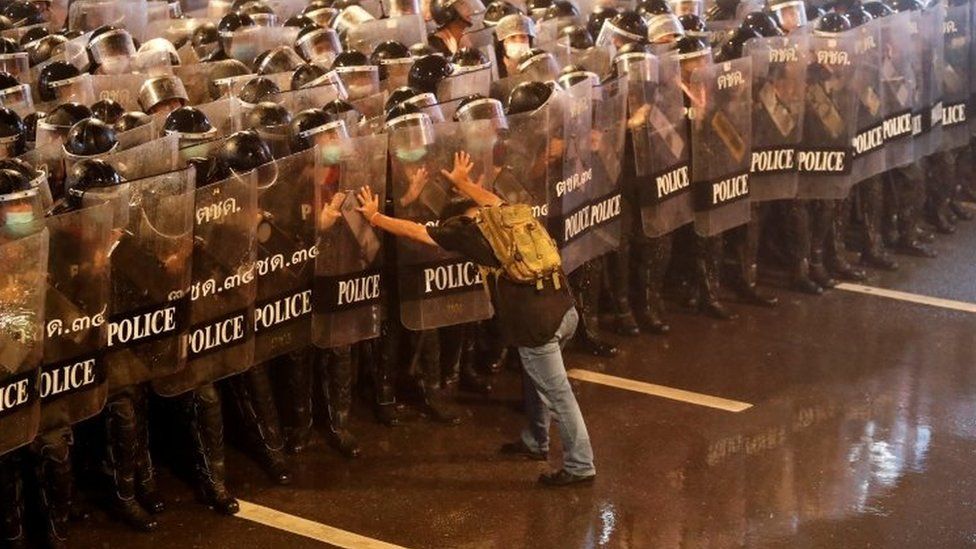 A man pushes against riot police officers in Bangkok, Thailand. Photo: 16 October 2020