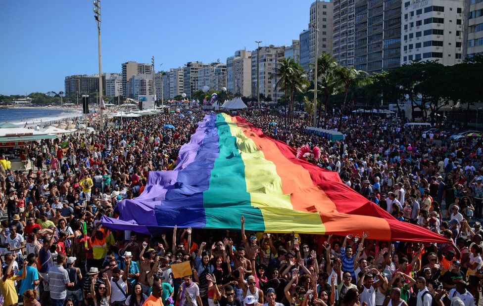 Revellers march with a giant rainbow flag during the annual Gay Pride Parade at Copacabana beach in Rio de Janeiro, Brazil