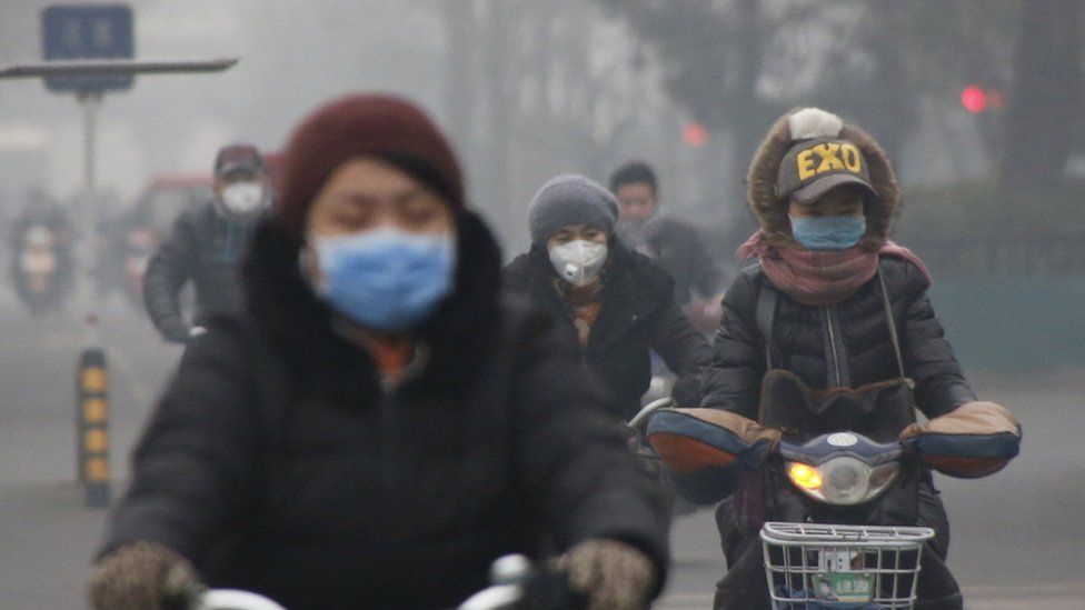 Cyclists riding through Beijing smog
