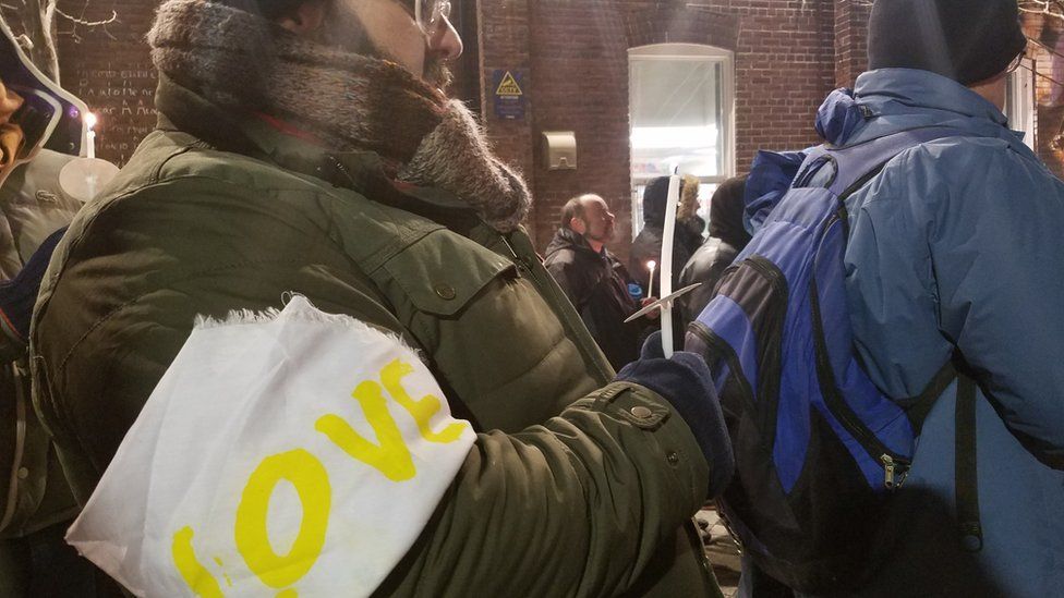 An attendee at the vigil wears an armband with the word "love"