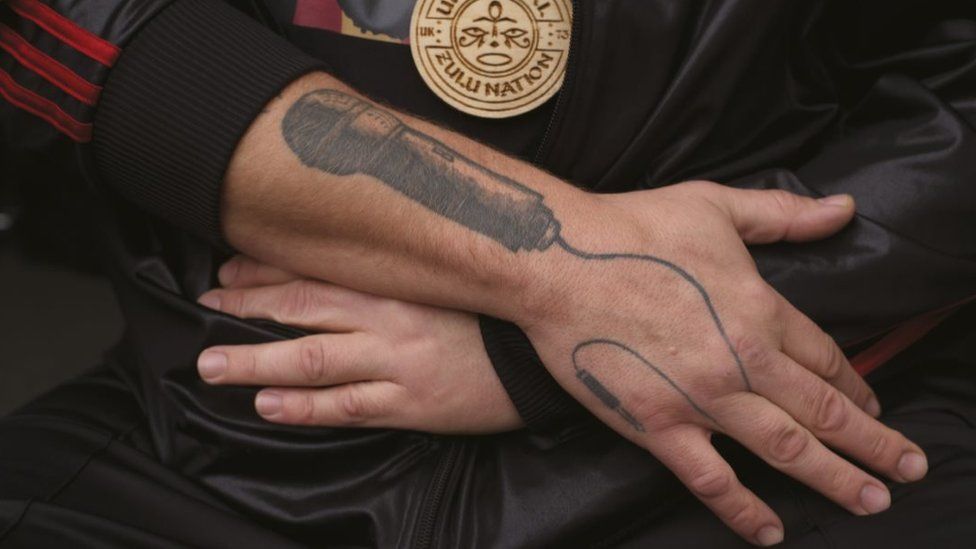 Close up showing tattoo of microphone on Steve's lower arm