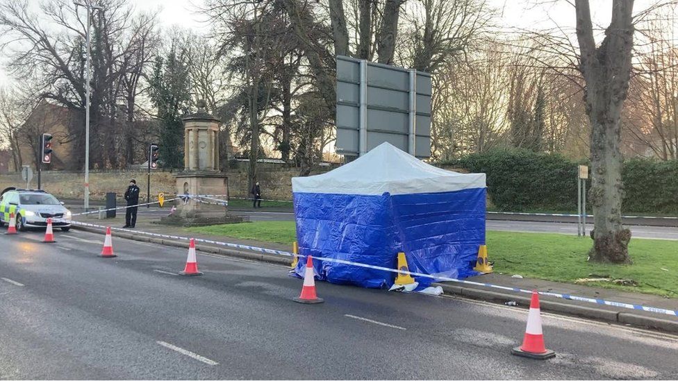 Forensic scene guard (blue tent) on the edge of a pavement by a busy roads, with road cones protecting it