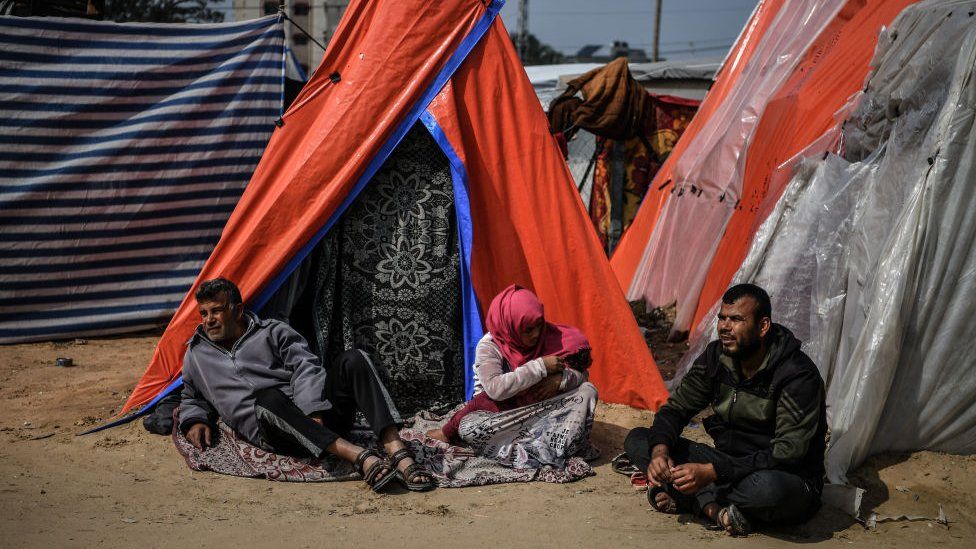 People sit outside tents in the city of Rafah