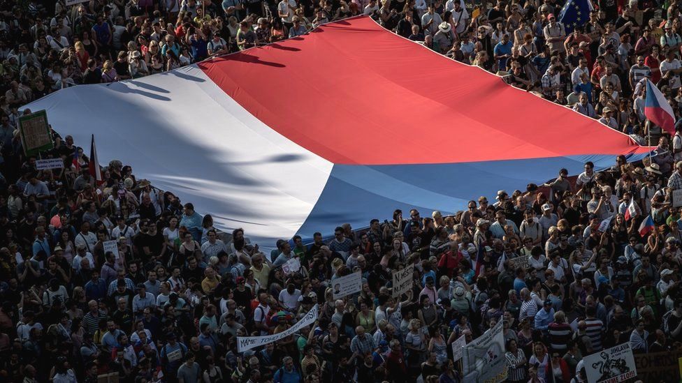 People carry a large Czech national flag as thousands of demonstrators gather to protest against Czech Prime Minister Andrej Babis on 4 June