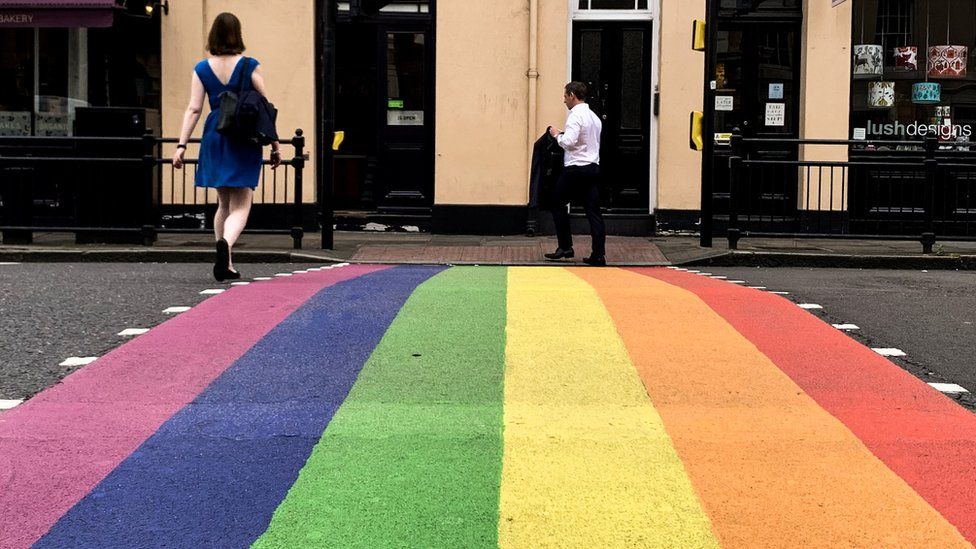 People on a LGBTQ rainbow street crossing in London