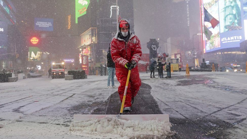 A worker clears snow as snow begins to fall in Times Square, New York