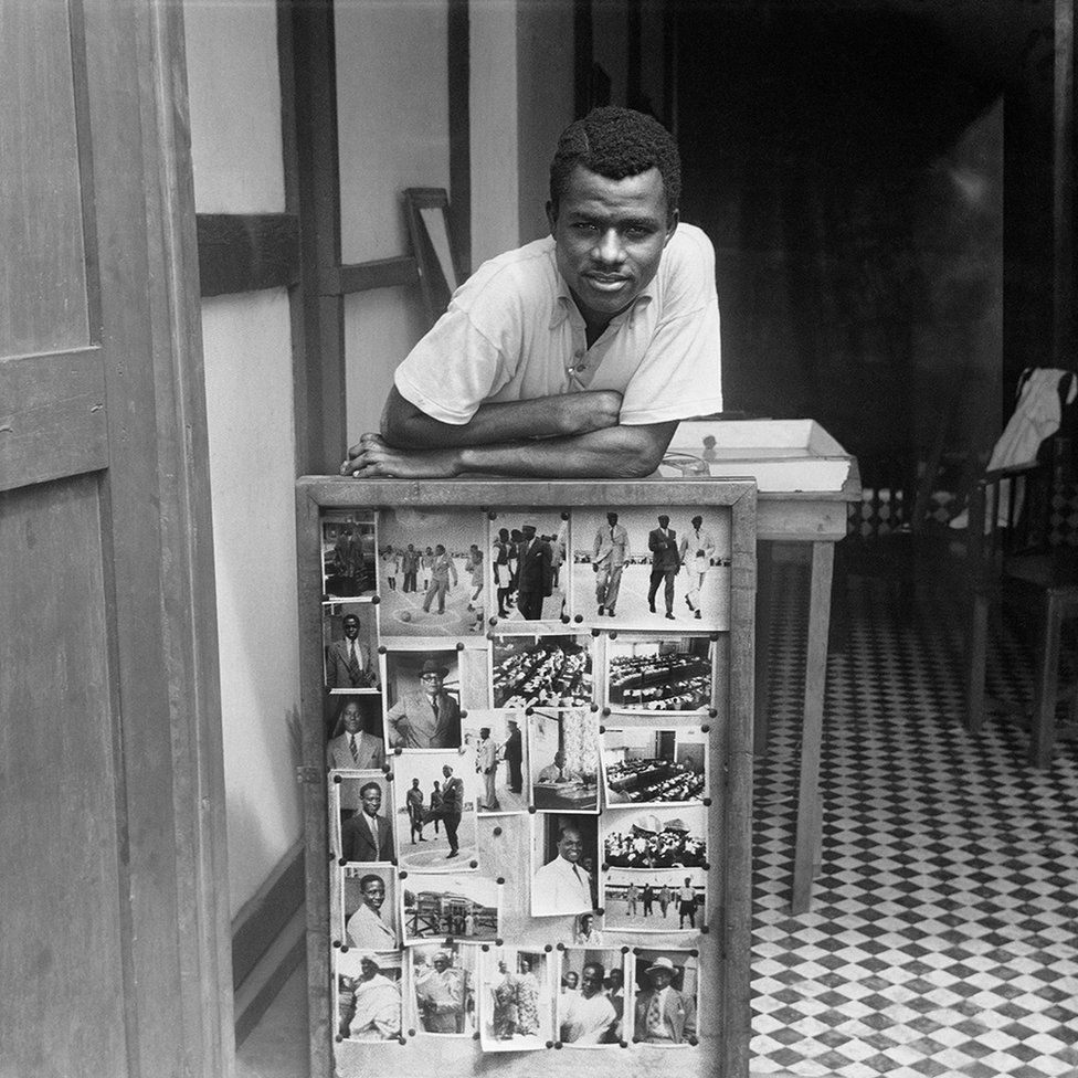 Portrait of James Barnor in front of some of his photographs