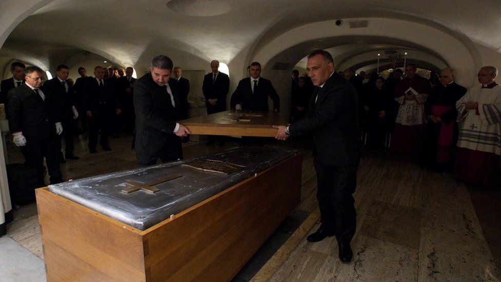 The wooden lid is placed upon Pope Benedict's coffin