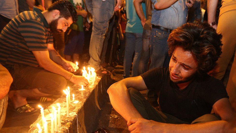 People light candles at the scene of a massive car bomb attack in Karada, Baghdad, 4 July