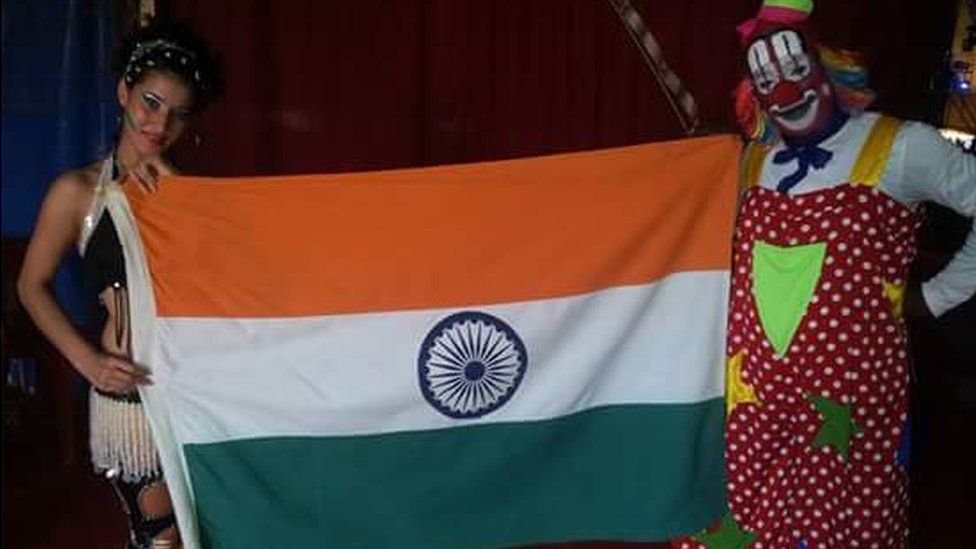 Performers at Rambo Circus hold up a national flag