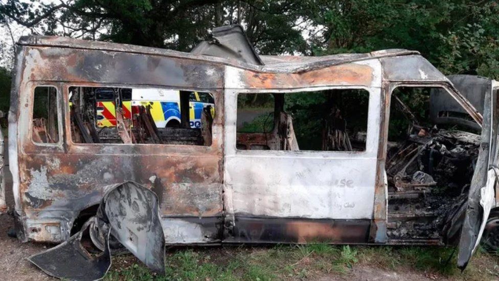 A minibus that has been burned out. Not much of the interior is left and part of it look like it began to melt.