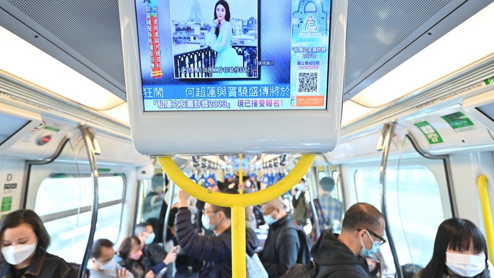 People on a Hong Kong train watching a screen
