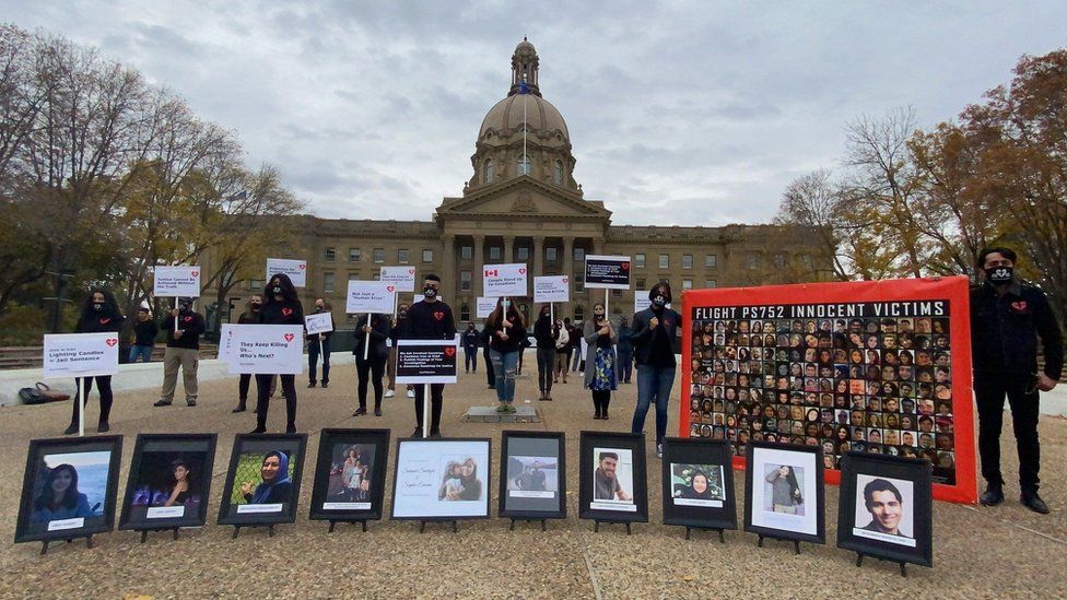 Families of PS752 victims standing outside Alberta's parliament building holding placards and images of those who died on PS752