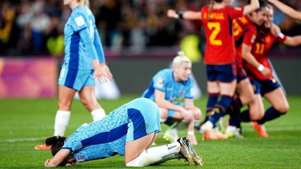 England players slumping to the ground as Spain players celebrate behind them