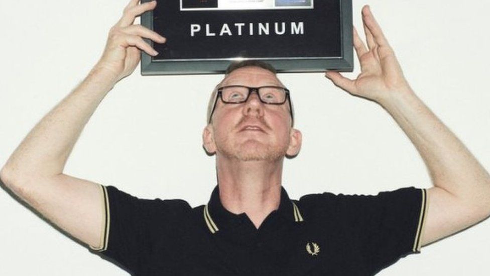 Dave Rowntree balances Calvin Harris' platinum disc above his head