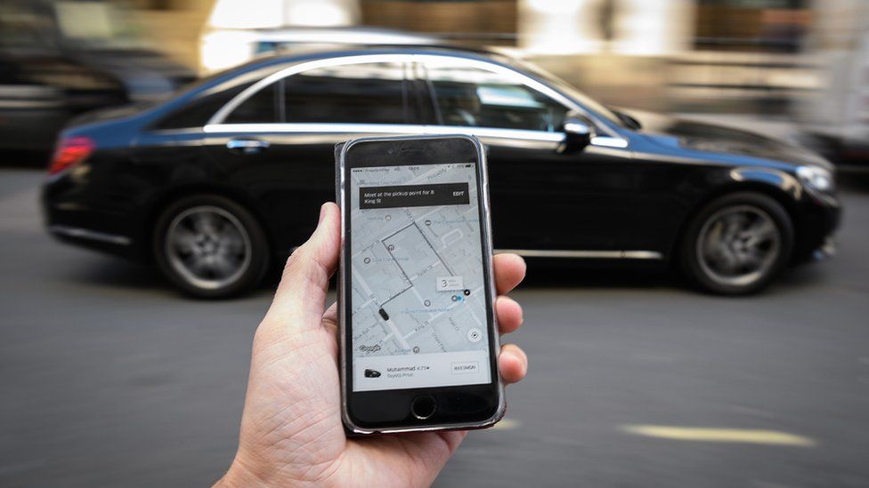 Uber app on a smartphone in front of a car