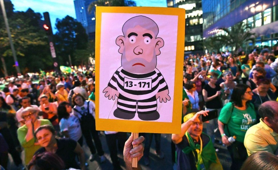 A crowd of anti-Lula demonstrators in Sao Paulo, Brazil. One carries a placard with a picture of a cartoon robber.