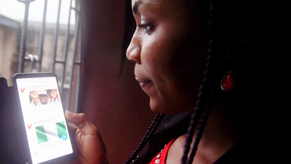 A woman in Nigeria looking at Twitter on a mobile phone - archive shot