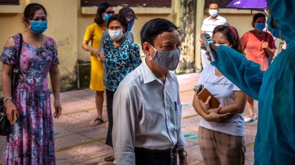 People who recently returned from Da Nang city wear face masks while queuing in safe distance to take the coronavirus disease rapid test on July 31, 2020 in Hanoi, Vietnam.