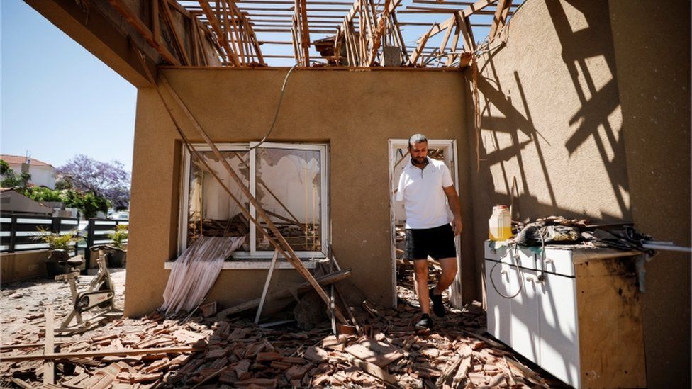 An Israeli man walks through his home in Sderot after it was hit by a rocket fired from Gaza