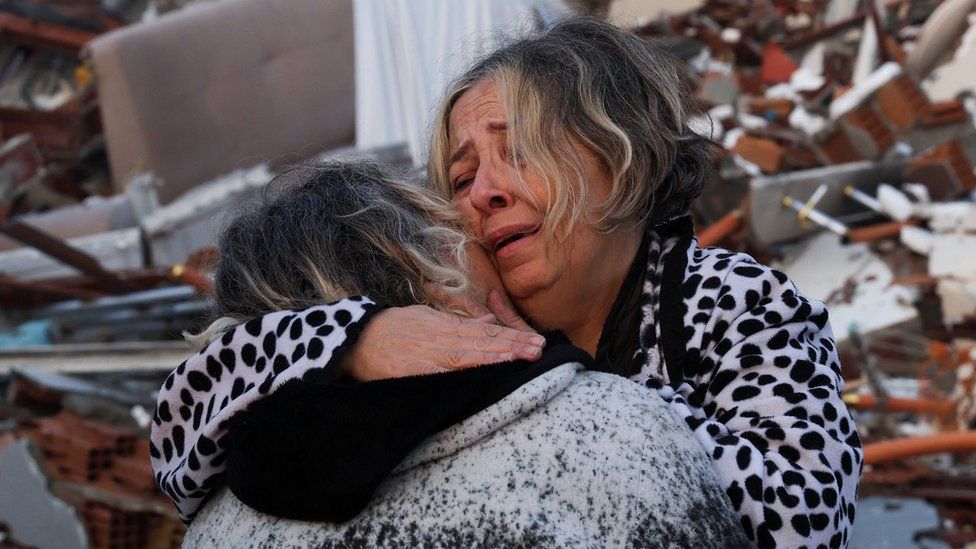 A woman reacts while embracing another person, near rubble following an earthquake in Hatay, Turkey, February 7, 2023