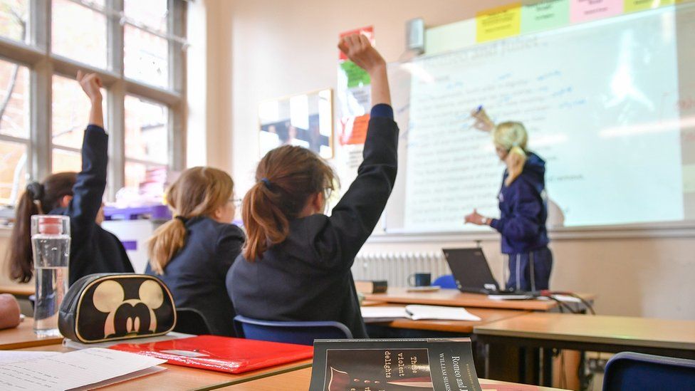 children raising their hand in a classroom