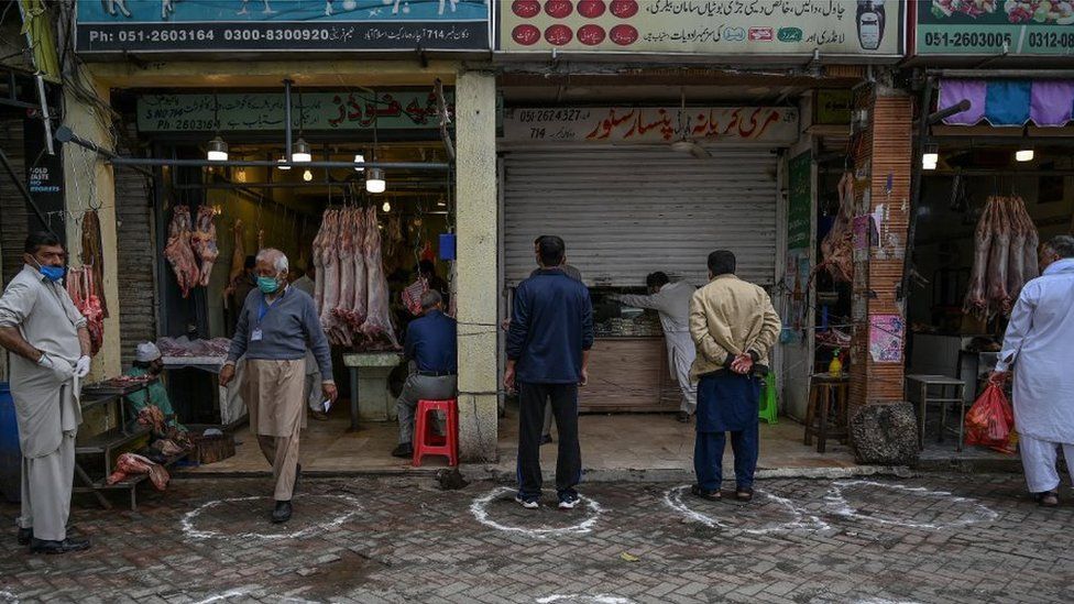 Customers stand in circles on ground, as part of social distancing measures, outside shops in Islamabad
