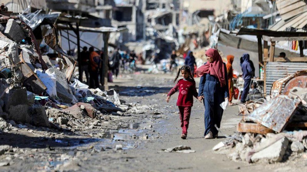 Palestinians walk past the ruins of houses destroyed during Israel's military offensive, amid the ongoing conflict between Israel and Hamas, in Gaza City, March 20, 2024