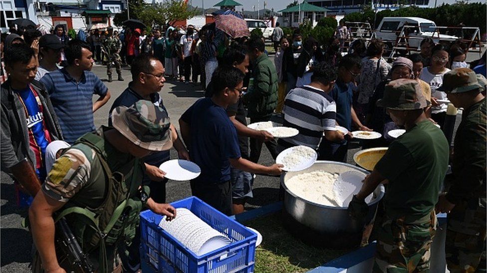 People queue up for a food distribution by the Indian army at Imphal airport on May 7, 2023, as they flee ethnic violence that has hit the northeastern Indian state of Manipur.