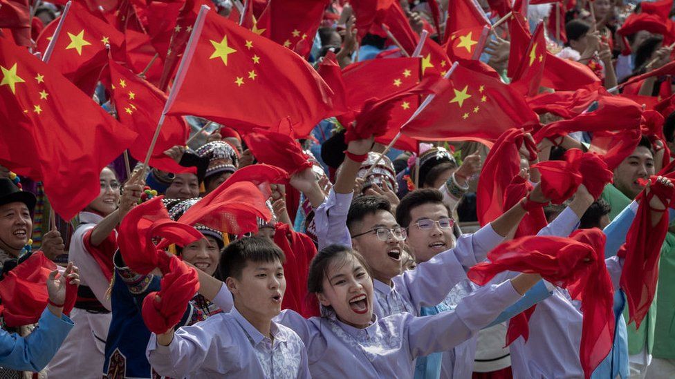 Chinese participants wave the national flag as they in a parade to celebrate the 70th Anniversary of the founding of the People's Republic of China in 1949,