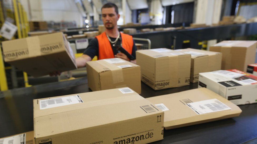 A worker prepares packages for delivery at an Amazon warehouse on September 4, 2014 in Brieselang, Germany.